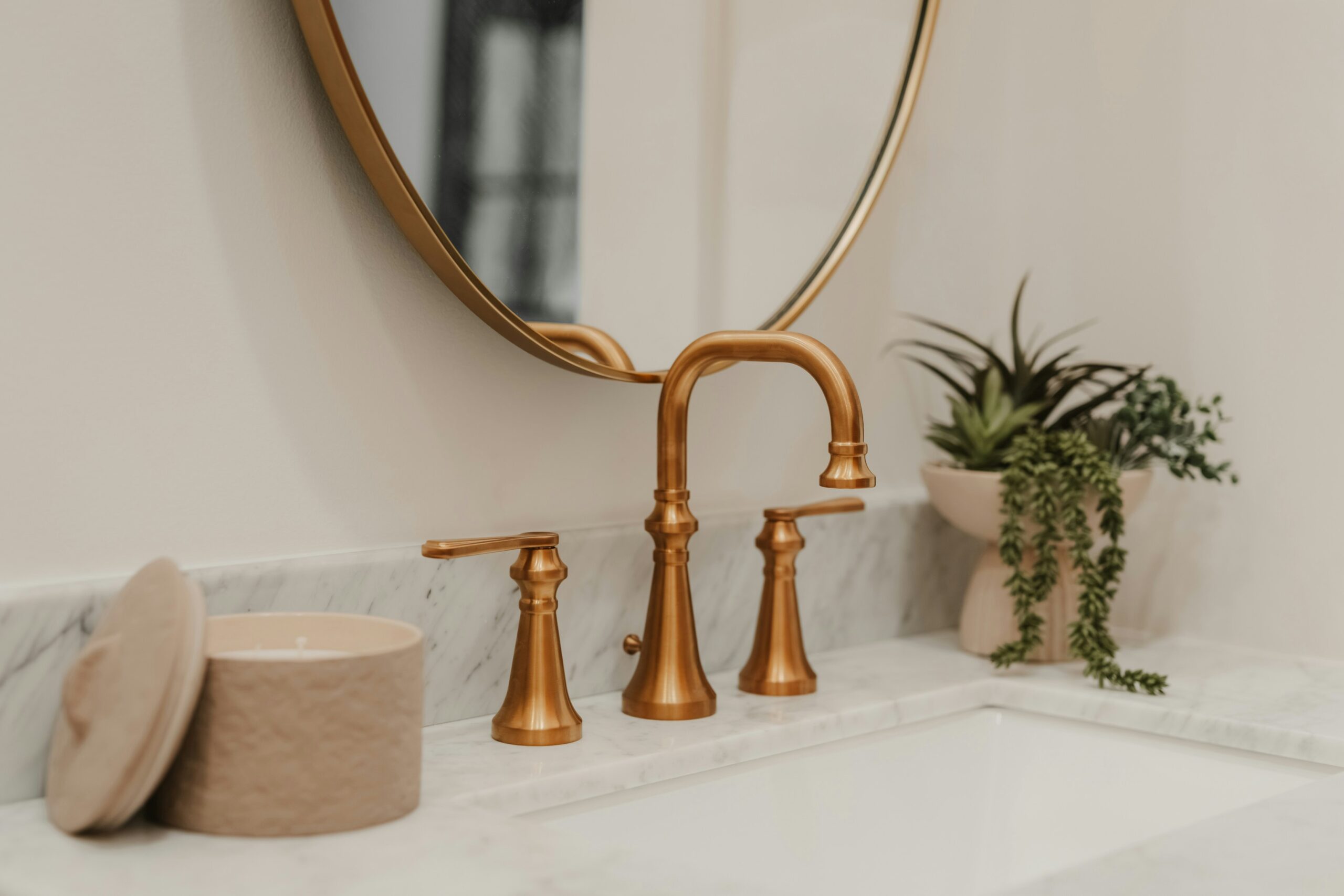 Brass bathroom faucet and mirror installed above marble sink