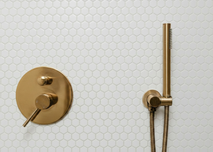 Brass shower fixtures installed on white tile